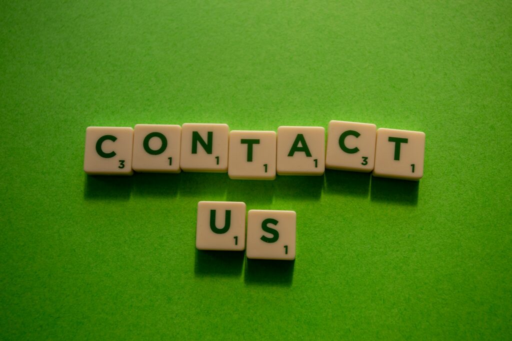 white and black dice on green textile spelling out "Contact Us"